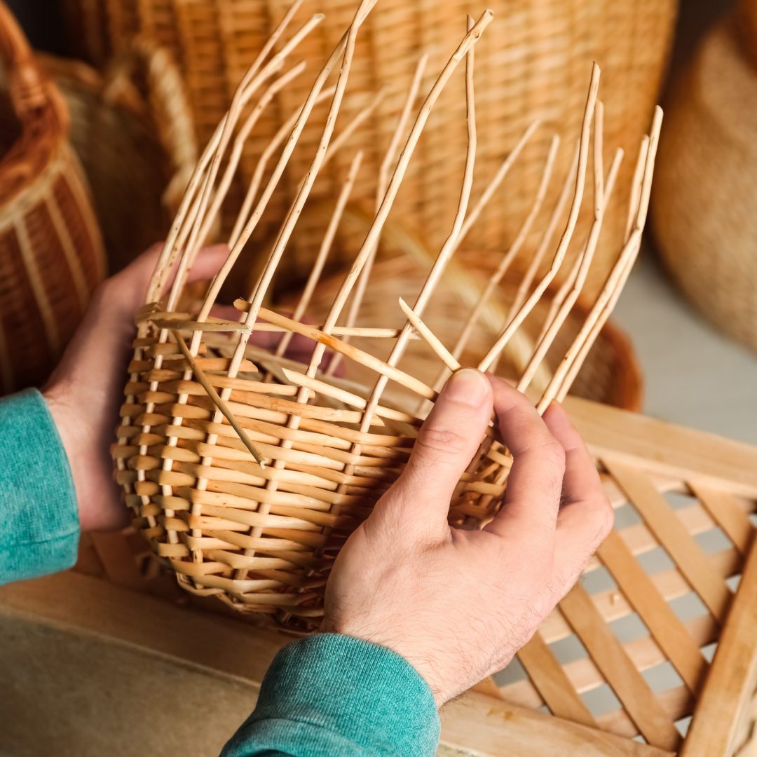 Man weaving wicker basket indoors, closeup view